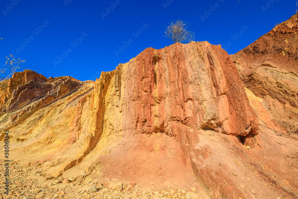 Vivid colors of Ochre Pits a minerals rock formation ochre on dry creek in West McDonnell Ranges. Popular destination in Northern Territory, Australia. Ochre is used by Aborigine people for ceremonies