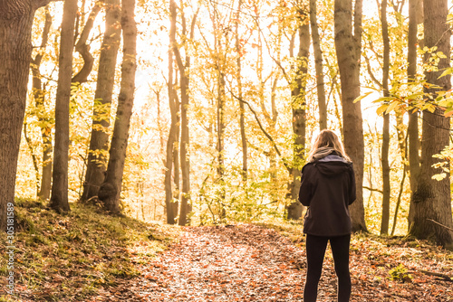 young woman walking in autumn woods in the morning sun.