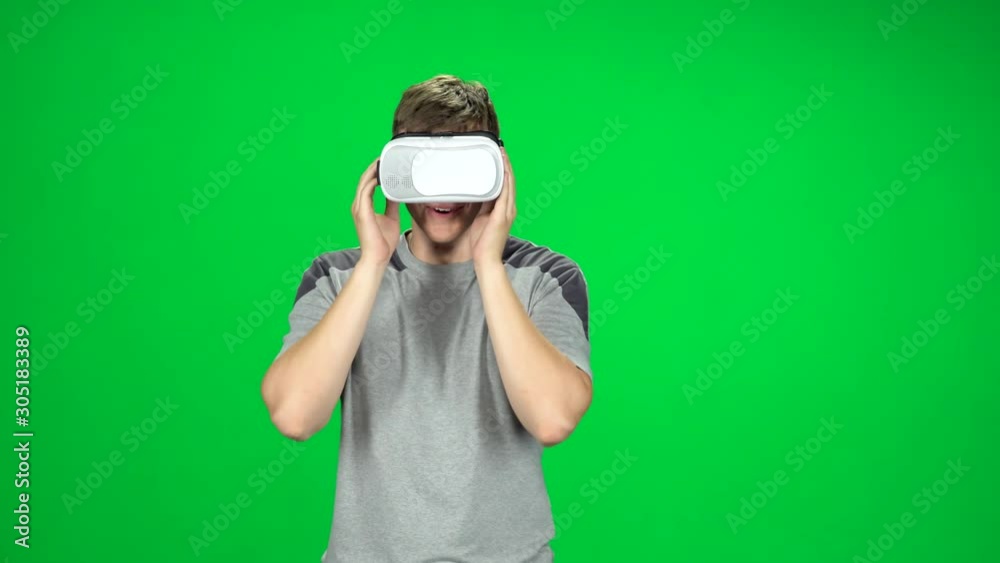 Smiling man wearing a virtual reality headset goes at the green screen Smiling man wearing a virtual reality headset goes at the green screen