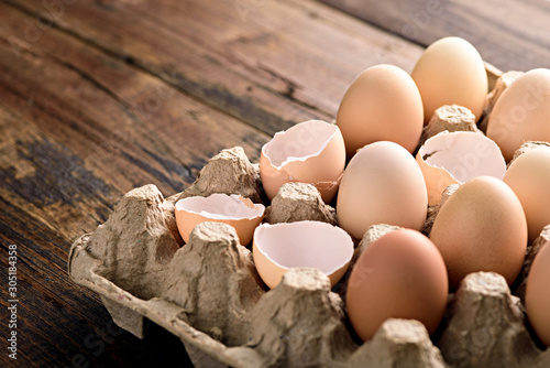 eggs with shells in eco-friendly cardboard box on brown background photo