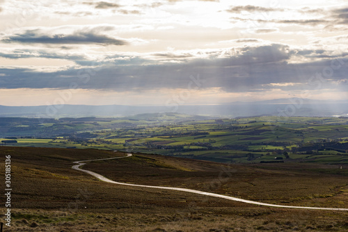 Cumbrian Landscape, Eden Valley, and distant Lake District hills taken from Hartside Top near Alston in the Pennines with rays from the setting sun breaking through the cloud
