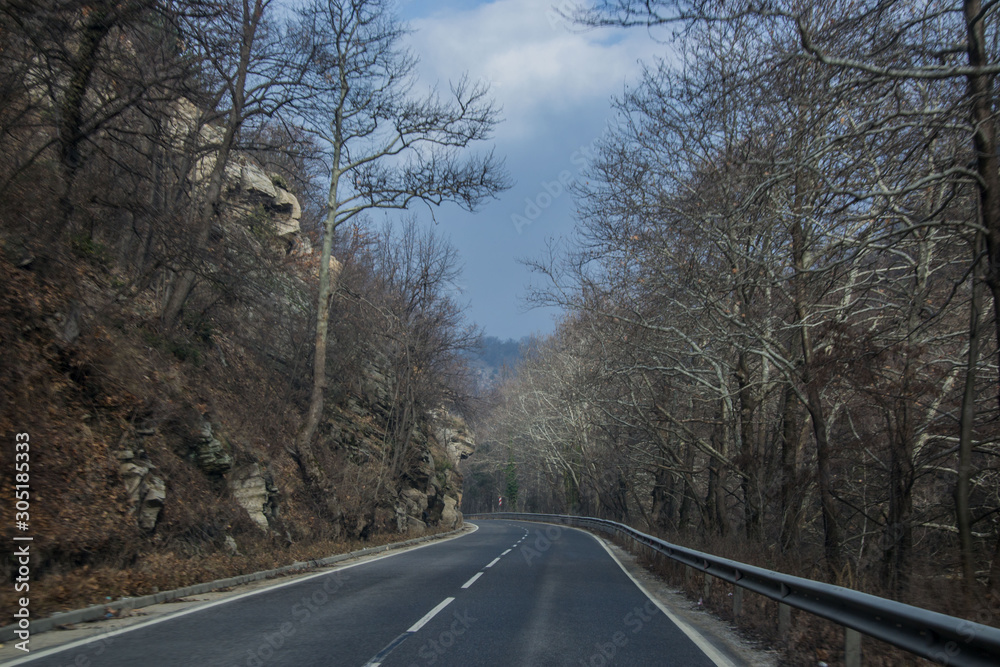 Fototapeta premium Beautiful mountain road in Bulgaria, Rhodopi mountain, wintertime car road with trees and rocks on the side