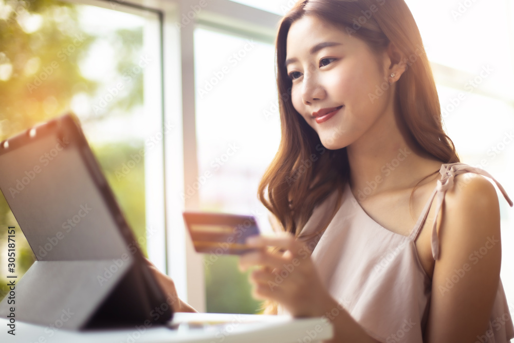 Happy Asian young woman doing online shopping at home.She holding credit card and using laptop computer.Smiling asian woman on couch using tablet to shop online n the living room. Happy Asian young woman doing online shopping at home.She holding credit card and using laptop computer.Smiling asian woman on couch using tablet to shop online n the living room.