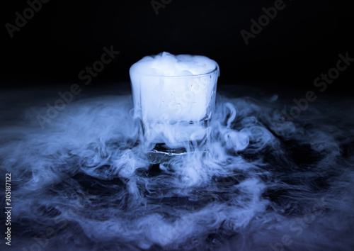 The smoke from dry ice in a glass, black background. photo