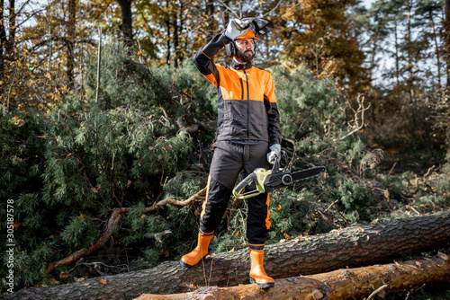 Fotografie Full length portrait of a professional lumberjack in protective workwear standin