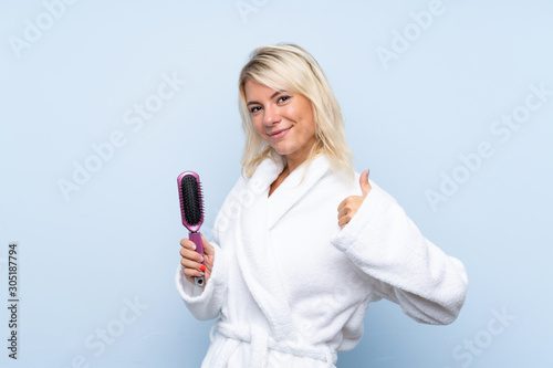 Young woman in a bathrobe with hair comb with thumbs up because something good has happened
