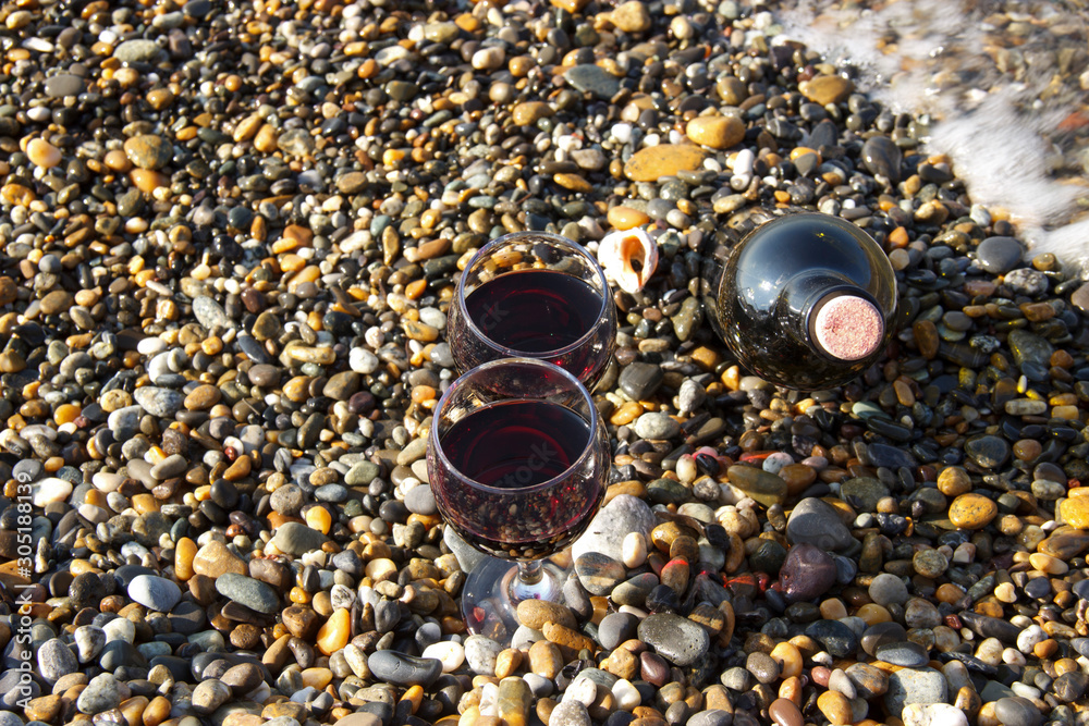 Romantic day with glasses of red wine, on the beach on a Sunny autumn day. Waves and sea in the background. The concept of the wedding Romantic day with glasses of red wine, on the beach on a Sunny autumn day. Waves and sea in the background. The concept of the wedding