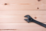 Old adjustable wrench on wooden surface. Work concept