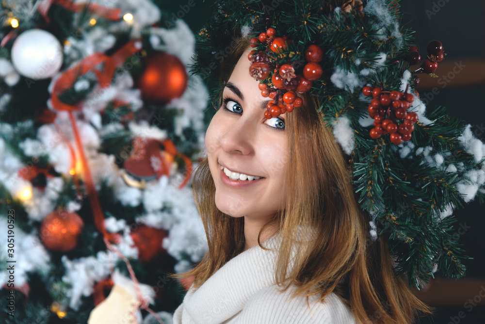 Smiling beautiful girl with mistletoe crown in front of Christmas tree Smiling beautiful girl with mistletoe crown in front of Christmas tree