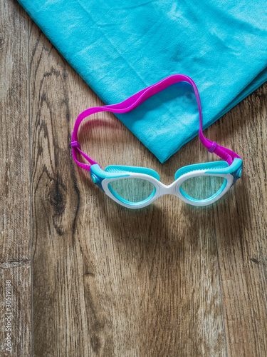 Swimming pool glasses with towel on wood background with copy sp