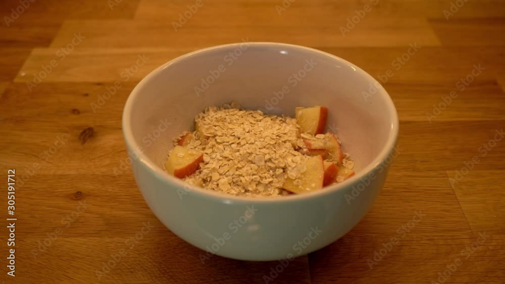 oats falling into a breakfast bowl - preparing a vegan breakfast with oats, fruit, omega-3, amaranth, raisins almonds and oat milk oats falling into a breakfast bowl - preparing a vegan breakfast with oats, fruit, omega-3, amaranth, raisins almonds and oat milk