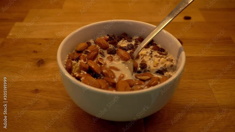 Flaxseed falling into a breakfast bowl - preparing a vegan breakfast with oats, fruit, omega-3, amaranth, raisins almonds and oat milk Flaxseed falling into a breakfast bowl - preparing a vegan breakfast with oats, fruit, omega-3, amaranth, raisins almonds and oat milk