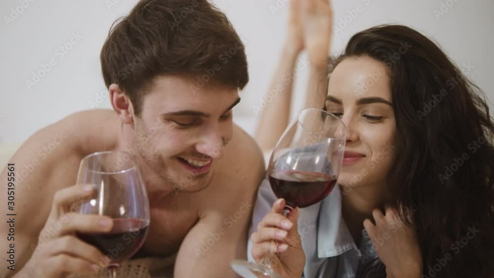 Cheerful couple clinking glasses in slow motion. Sexy man and woman tasting wine Cheerful couple clinking glasses in slow motion. Sexy man and woman tasting wine