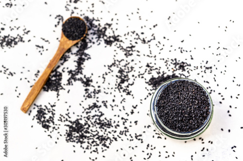 Black sesame seeds in a wood spoon with white background