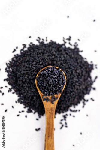 Black sesame seeds in a wood spoon with white background
