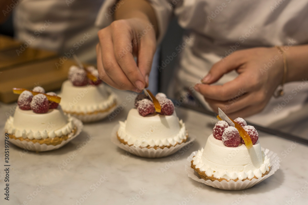Female hands decorating by berries tart with custard