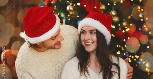 Man in love looking at his woman by Christmas tree