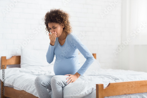 African-american expectant woman feeling nauseous, covering mouth