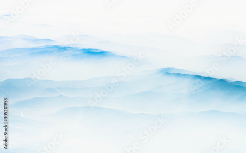 Aerial view of distant mountains layers range in morning mist. Meditation and zen landscape.