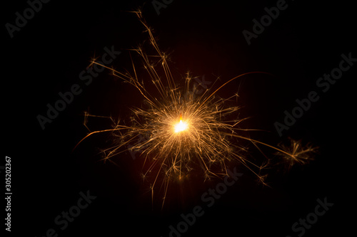 Burning sparkler on black background
