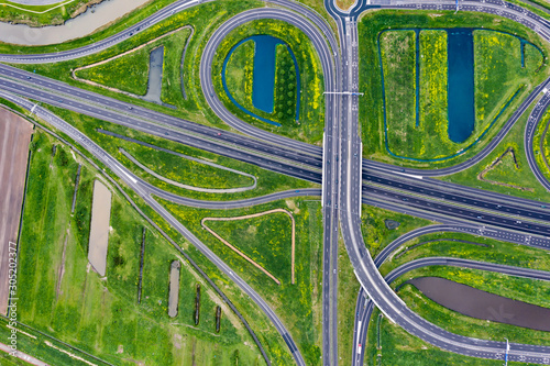 A cloverleaf highway with traffic in the middle of green fields near Waalwijk, Brabant, Netherlands