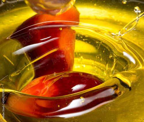 Red Palm seed dropped in cooking palm oil with a splash in glass. Organic palm oil can be processed for food industry and produce energy as biodiesel and important agriculture economy in tropical Asia