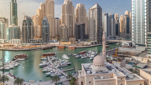 Yachts in Dubai Marina flanked by the Al Rahim Mosque and residential towers and skyscrapers aerial timelapse. photo