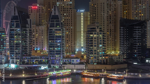 Luxury yachts parked on the pier in Dubai Marina bay with city aerial view night timelapse