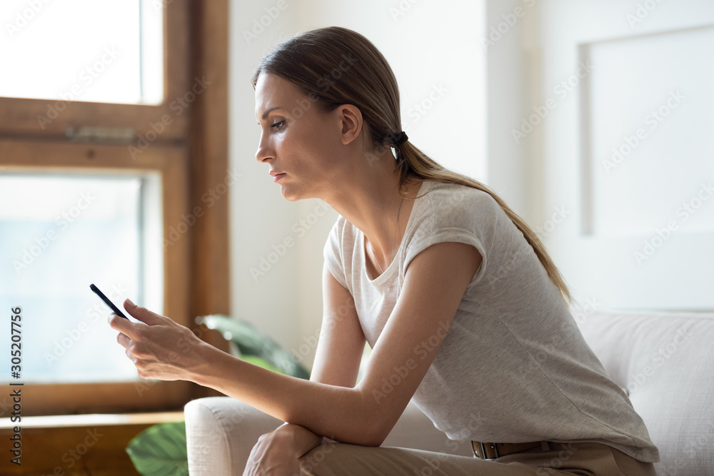 Thoughtful young woman looking at mobile phone screen. Thoughtful young woman looking at mobile phone screen.