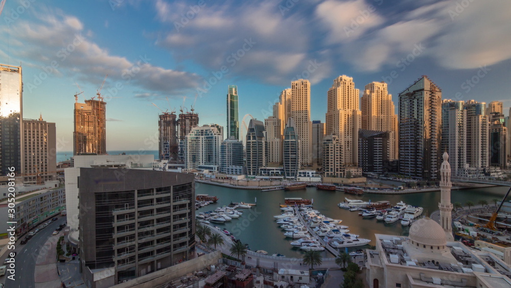 Yachts in Dubai Marina flanked by the Al Rahim Mosque and residential towers and skyscrapers aerial timelapse.