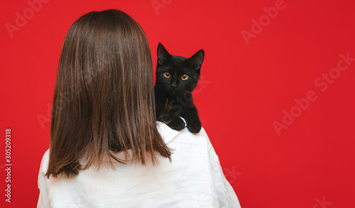 Canvas Print Cute black cat sits on the owner's back and looks into the camera