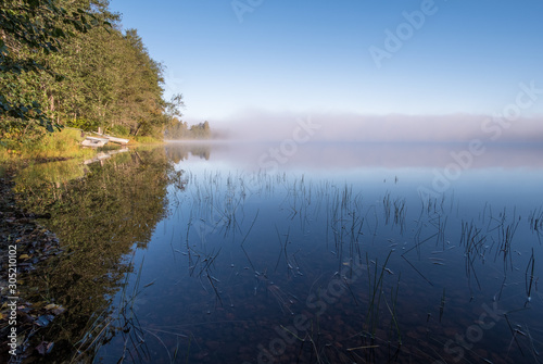 Idyllic lake landscape with sunrise light and standing water at summer morning in National Park Finland