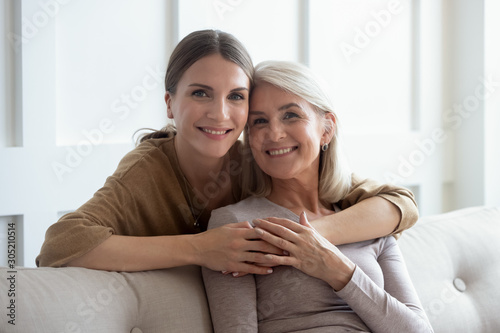 Head shot smiling young woman embracing middle aged mother.