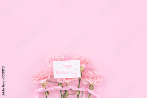 Beautiful, fresh elegant carnation flower bouquet with white greeting thanks gift card isolated on bright pink color background, top view, flat lay concept. © RomixImage