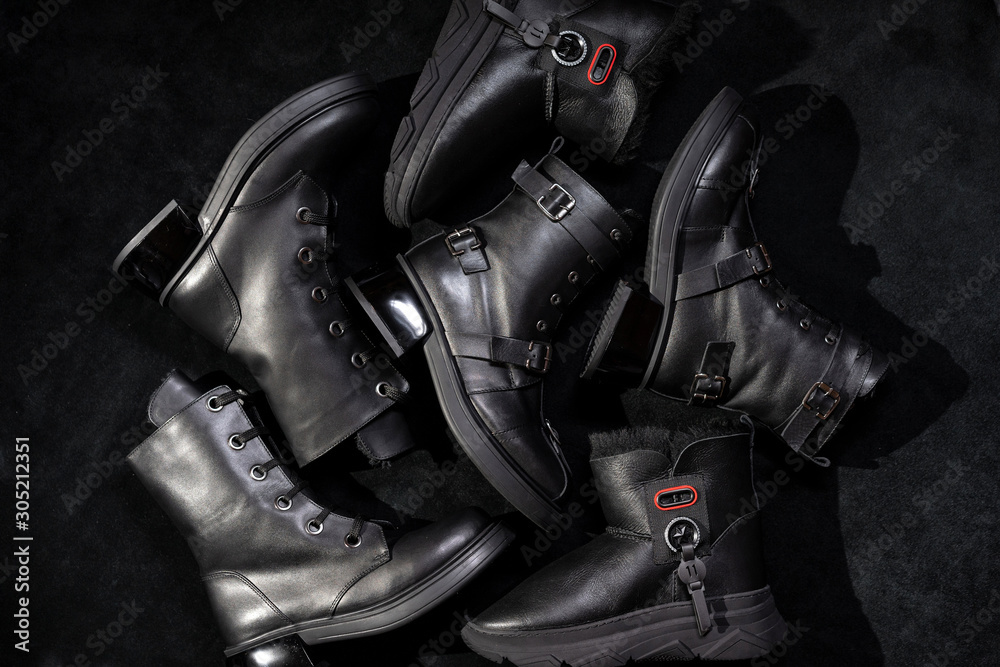 set of black leather boots with buckles and laces on a dark background. set of black leather boots with buckles and laces on a dark background.