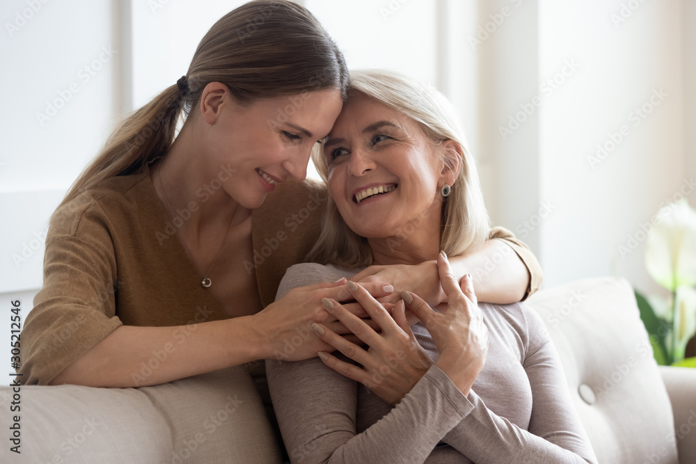 Head shot happy adult young woman embracing smiling older mommy. Head shot happy adult young woman embracing smiling older mommy.