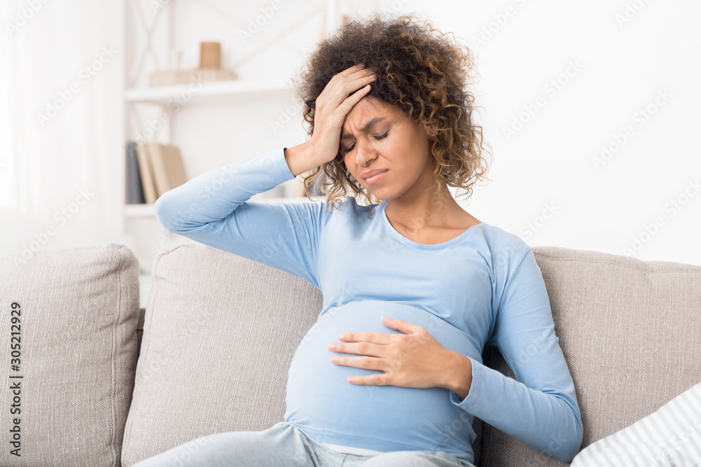 Pregnant afro girl suffering from headache at home Pregnant afro girl suffering from headache at home