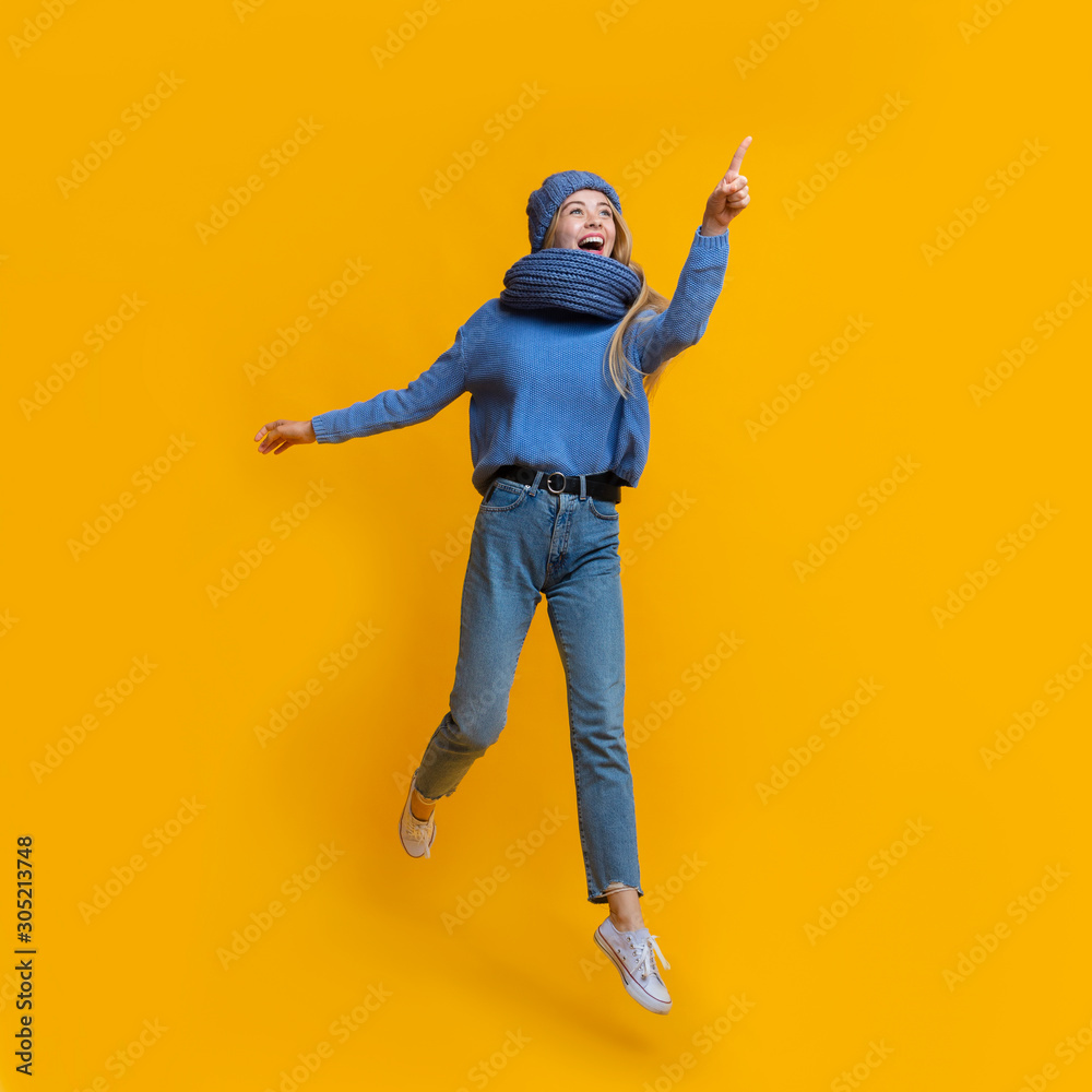 Amazed winter girl jumping and pointing somewhere Amazed winter girl jumping and pointing somewhere