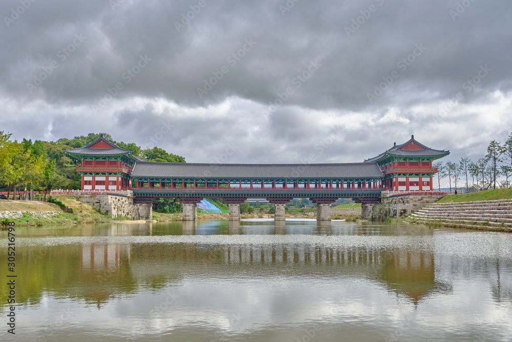 Fototapeta premium Scenic view of Woljeonggyo Bridge over Hyeongsan River in Gyeongju in South Korea. Beautiful summer cloudy look of colorful traditional asian style bridge over creek in Republic of Korea.