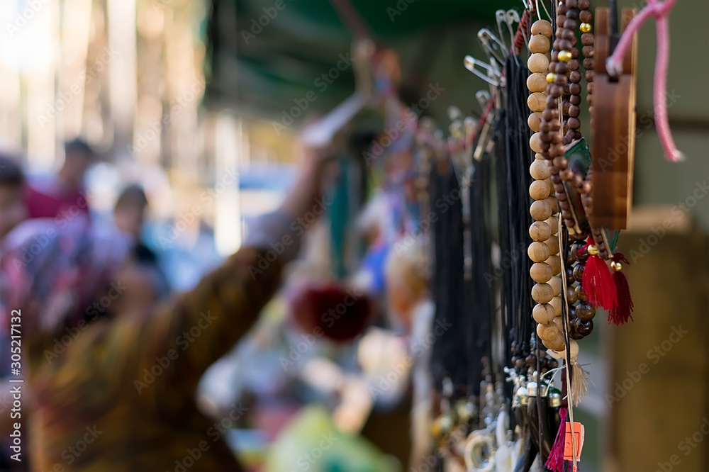 Obraz premium beads and jewelry hang on the street in the Asian market against the background of sellers and buyers who choose the goods