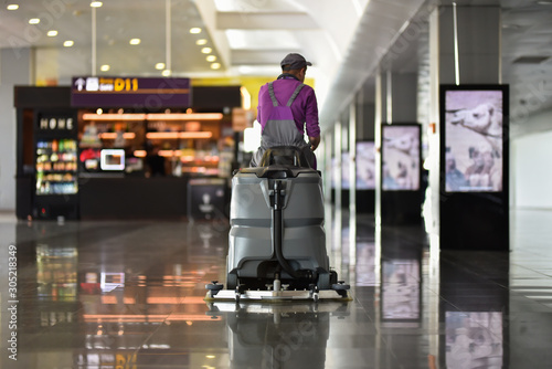 Man driving floor scrubber or floor cleaning device in airport
