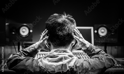 Photography back of asian male music producer feel disappointed at bad sound in recording studio