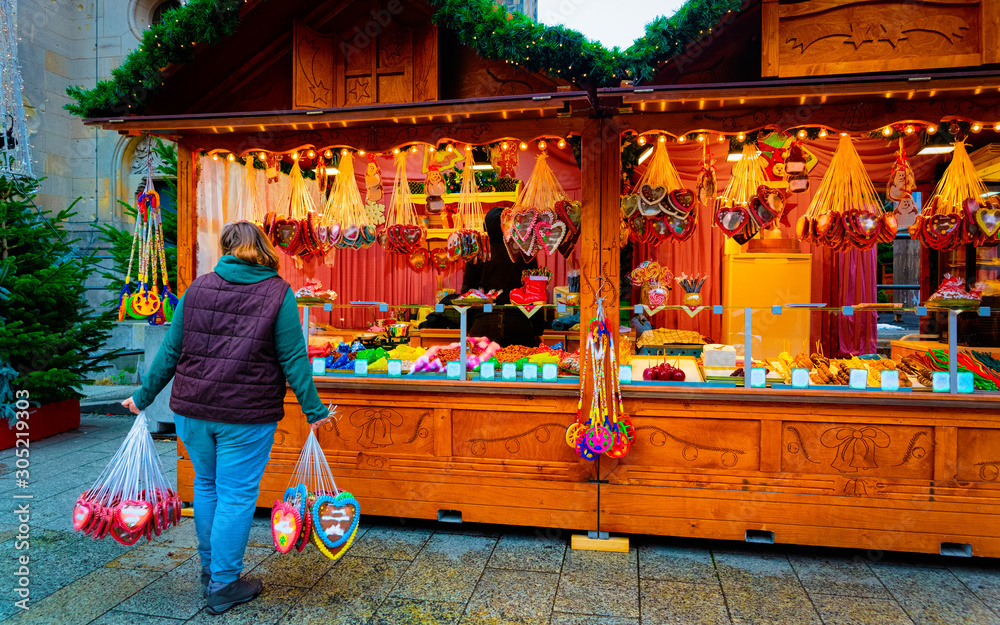 Obraz premium Woman with Gingerbread cookies food on Christmas market in Europe in winter. German Night street Xmas and holiday fair in European city or town, December. Kaiser Wilhelm Memorial Church in Berlin