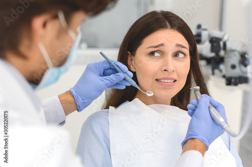 Fotografía Scared woman at dental office, looking panickly at dentist