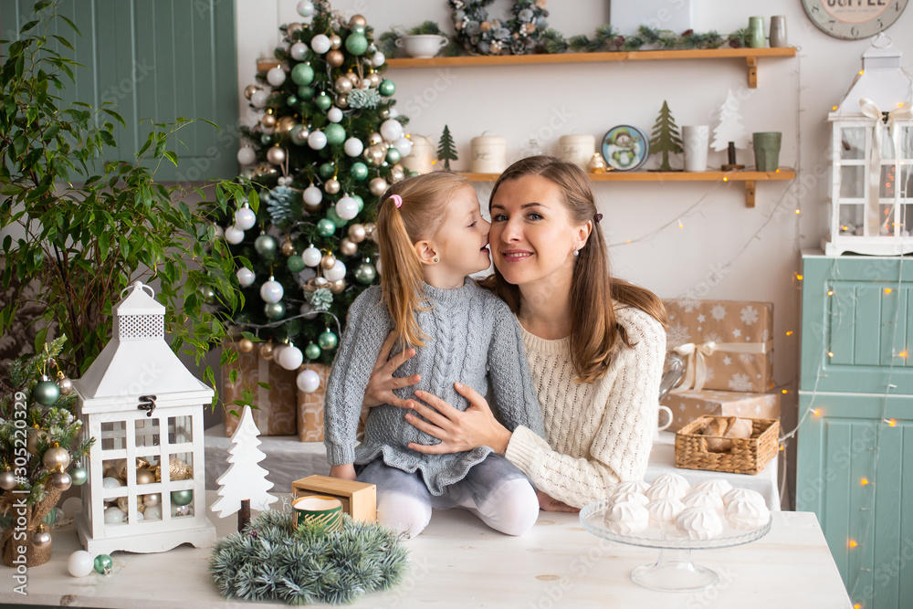 mother and daughter kissing in Christmas kitchen at home.