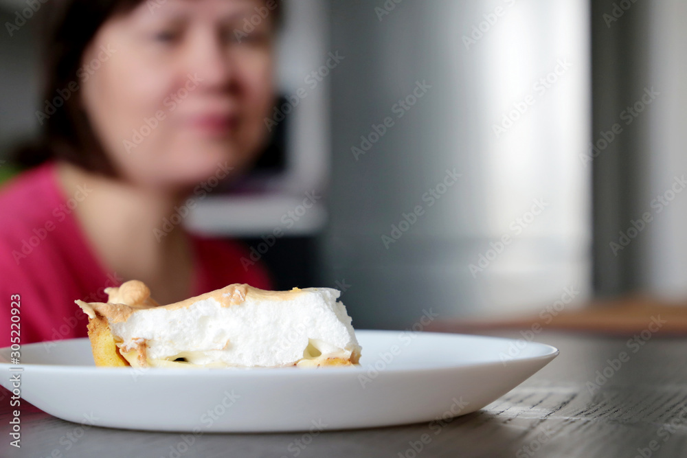 Diet and gluttony, woman looking on piece of sweet pie in a plate, selective focus. Tasty cake close up, concept of temptation by delicious food, sweet tooth