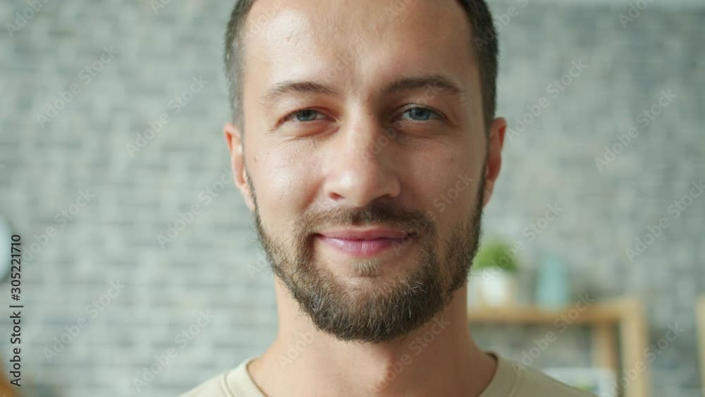 Slow motion portrait of a happy middle-aged guy smiling indoors in apartment looking at camera with happy face. Emotions, house and lifestyle concept. Slow motion portrait of a happy middle-aged guy smiling indoors in apartment looking at camera with happy face. Emotions, house and lifestyle concept.