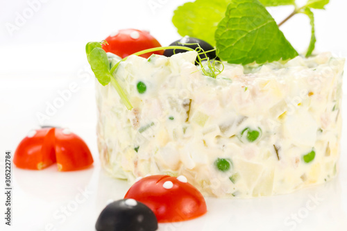 Olivier salad decorated with tomatoes on a white background restaurant