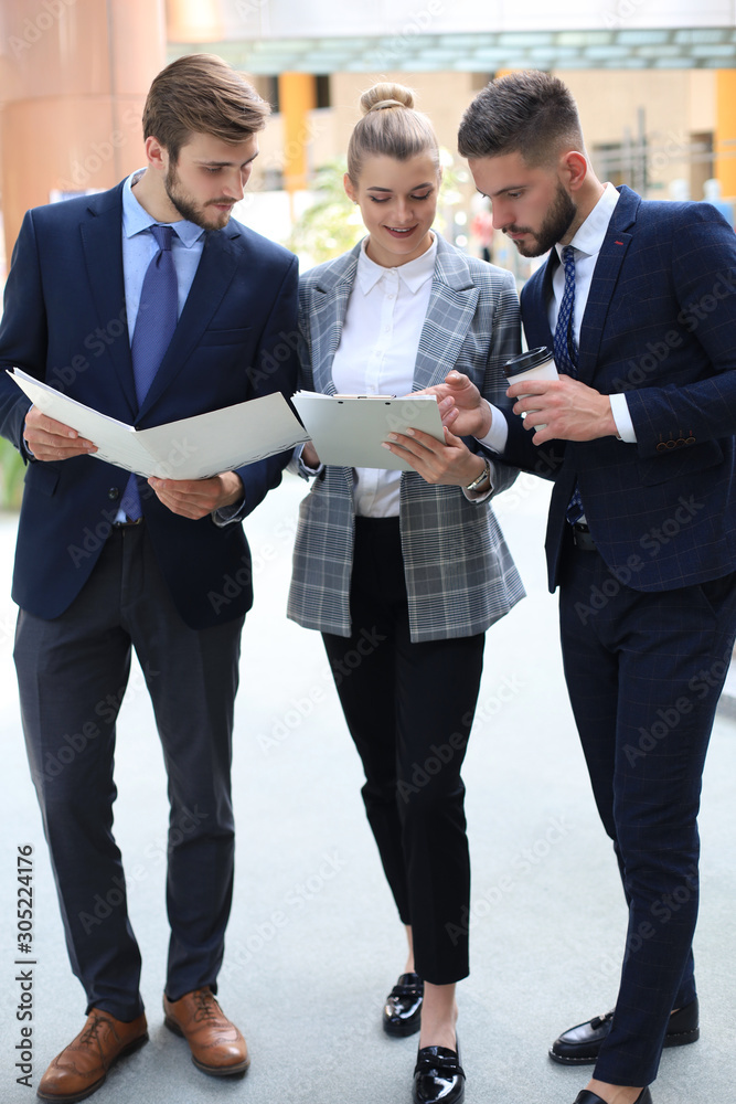 Fototapeta premium Three young businessmen standing discussing business at an office meeting.