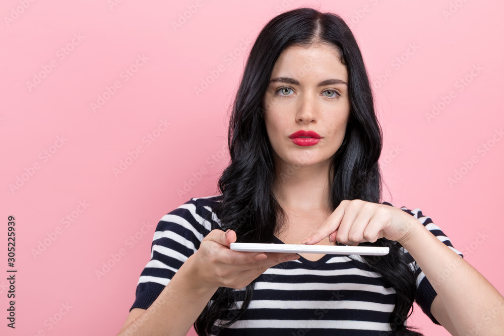 Young woman using her tablet on a pink background